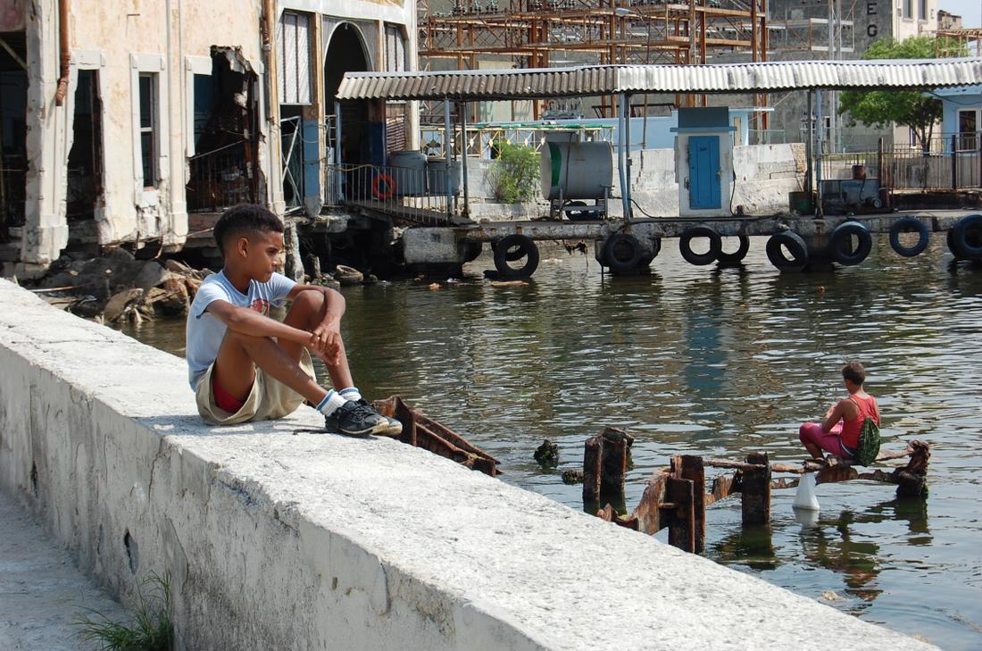 A Cuban boy watches friends play in Havana Bay.Photo: Katie Leslie / kleslie@ajc.com