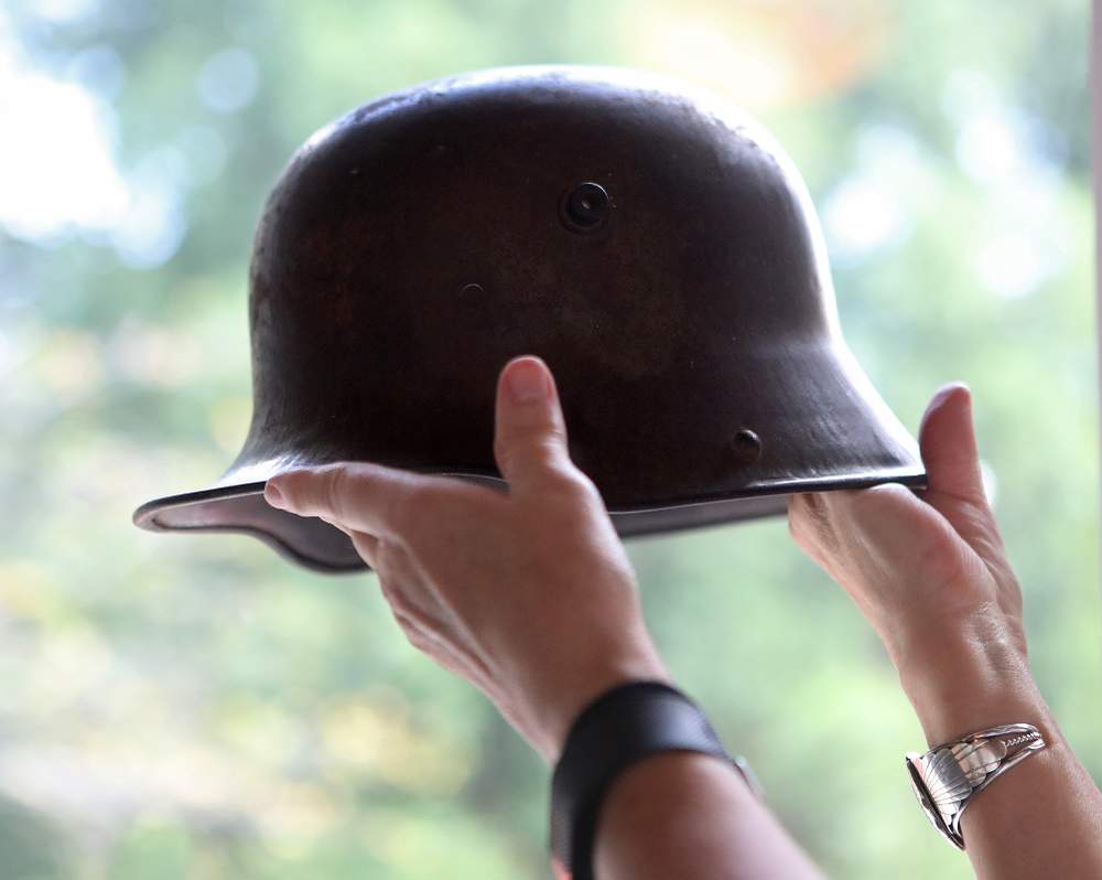 Ellen Hartman holds a German soldier's helmet that her father Joseph D. Weaver brought home from WW II at her home in Atlanta.  \/ Curtis Compton \/ccompton@ajc.com