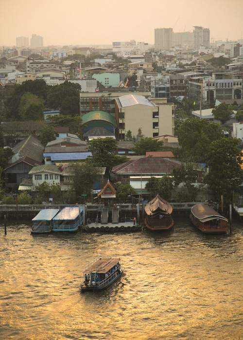 Sunlight reflects golden off of the Chao Phraya River. View from the Mandarin Oriental in Bangkok, March 2016.