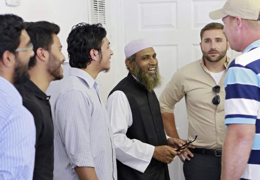 Imam Mohammad Islam (center) and members of the Masjid At-Taqwa Mosque (left) host Newton County residents for lunch at the existing Doraville place of worship. Islam believes in face-to-face outreach as a way of educating non-Muslims.PHOTO: Bob Andres \/ AJC