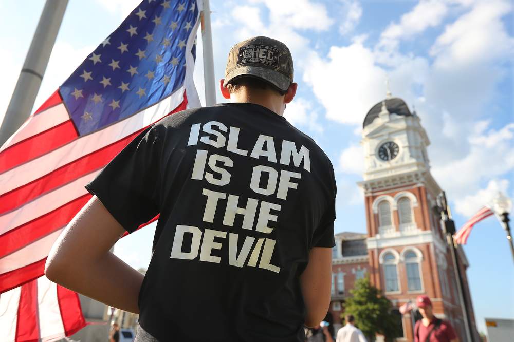 A young man stands across from the historic Newton County courthouse during a September 2016 protest organized by the III% Georgia Security Force. The group opposes building a mosque in the county.PHOTO:  Curtis Compton \/ AJC