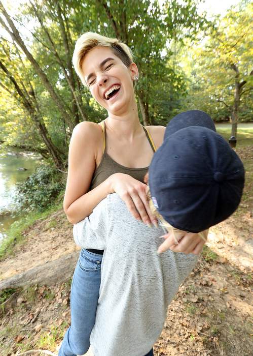 Emma gives her sister Hannah a hoist in the air as they share a laugh during a family outing.