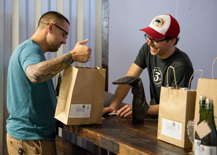 Joran Van Ginderachter, brewmaster at Three Taverns, gives a visitor his souvenir bottles of Inceptus at the brewery's first bottle release. Photo by Kathy Reynolds\/Three Taverns Brewery