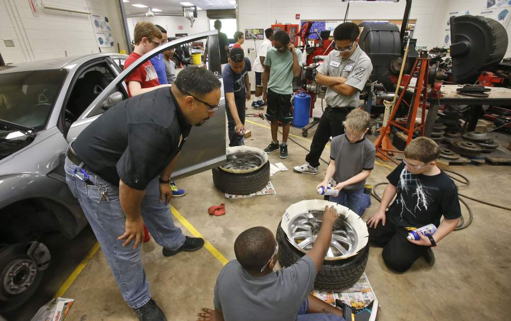 <strong>Teacher Max Chavez</strong> shows students how to plastic dip wheel rims in Maxwell High's Auto Services Shop. The Gwinnett school specializes in vocational education.<br /><br /><strong>Photo: Bob Andres / AJC</strong>