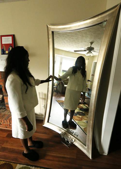 Loretta touches the full-length mirror in the living room of her home. It belonged to her daughter Nicole and is one of her most prized possessions.
