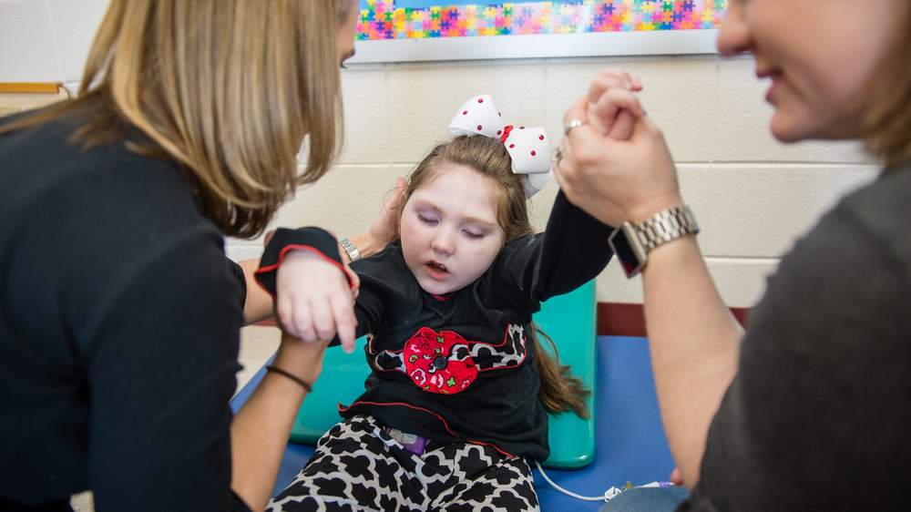 Haleigh receives therapy from physical therapist Julie Sullens (from left) at Hubbard Elementary School in Forsyth.