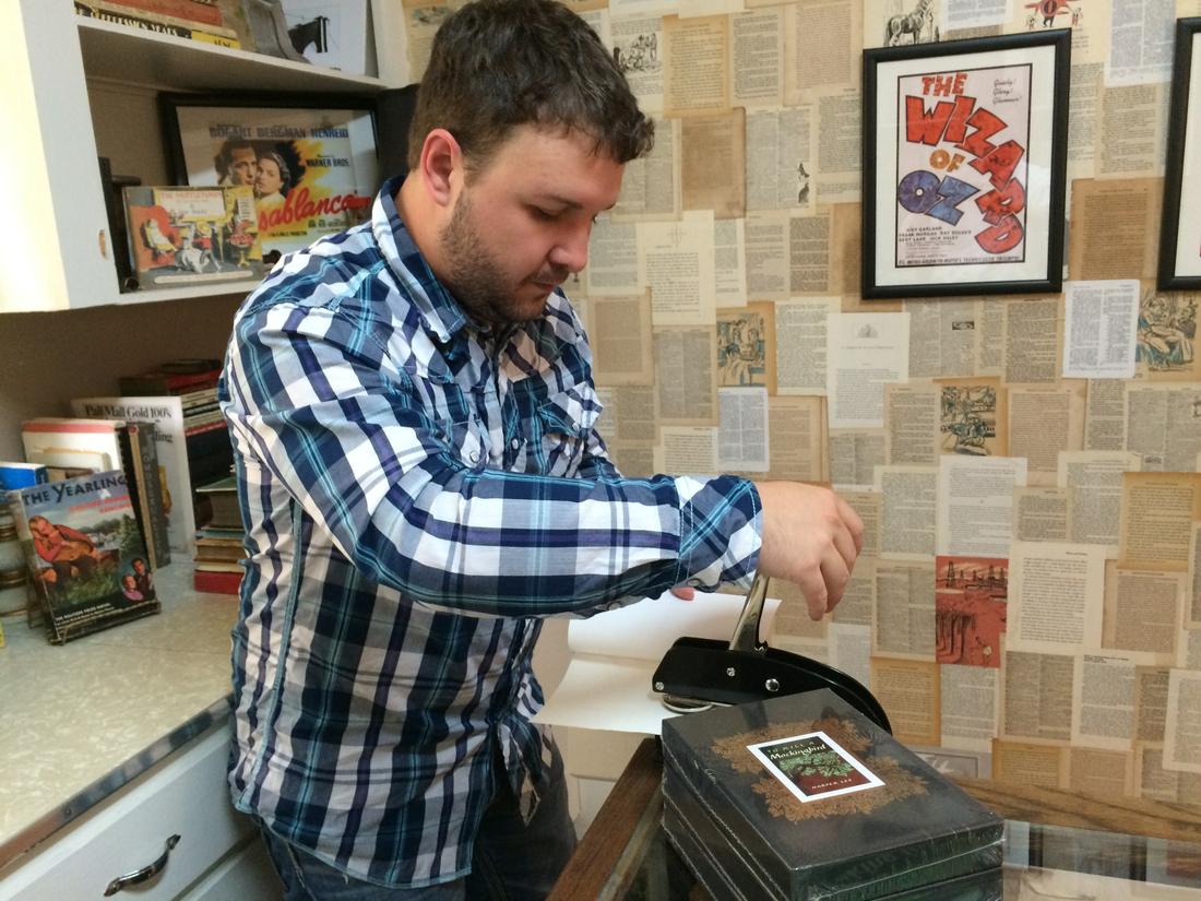 Spencer Madrie, co-owner of the Ol' Curiosities &amp; Book Shoppe in Monroeville, embosses a book with his store's name and address. Customers buying embossed copies of Harper Lee's "Go Set a Watchman" at the store will have proof they bought from Lee's hometown.
