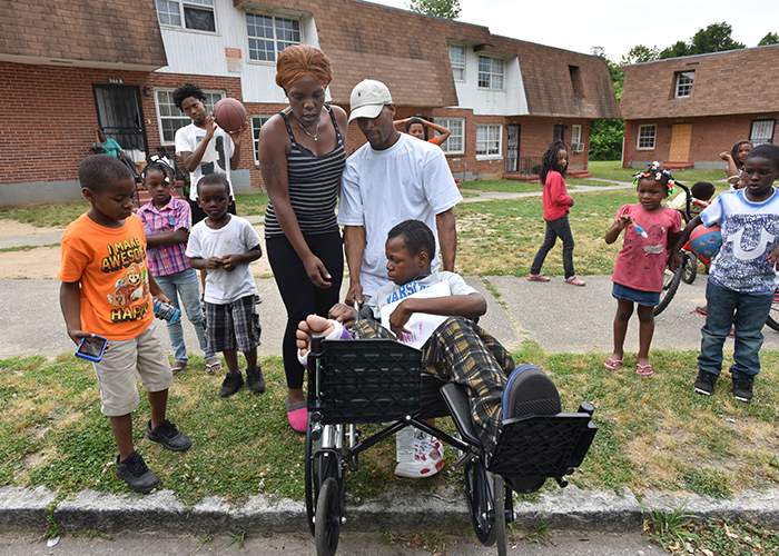 Teresa Lawrence (center left) helps her son Timothy to their home as friends and neighbors gather to greet him upon his return from rehabilitation. (Hyosub Shin \/ hshin@ajc.com)