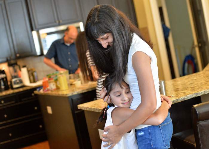 Anjali gets a hug from her daughter Siri, 8.