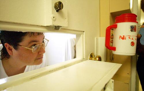 Gissendaner  peers through the slot in her cell door as a guard brings her a cup of ice in 2004 at Metro State Prison in Atlanta.<br /><em>(BITA HONARVAR / AJC staff)</em>