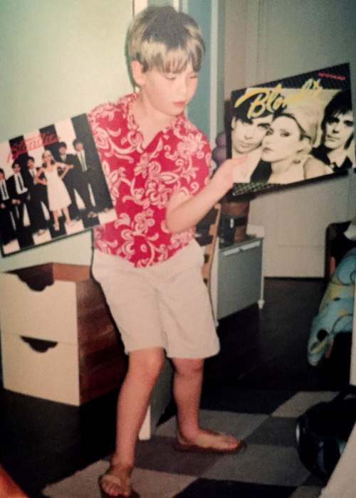 Addison with the Blondie album covers that decorated the walls of his room when he was a child.