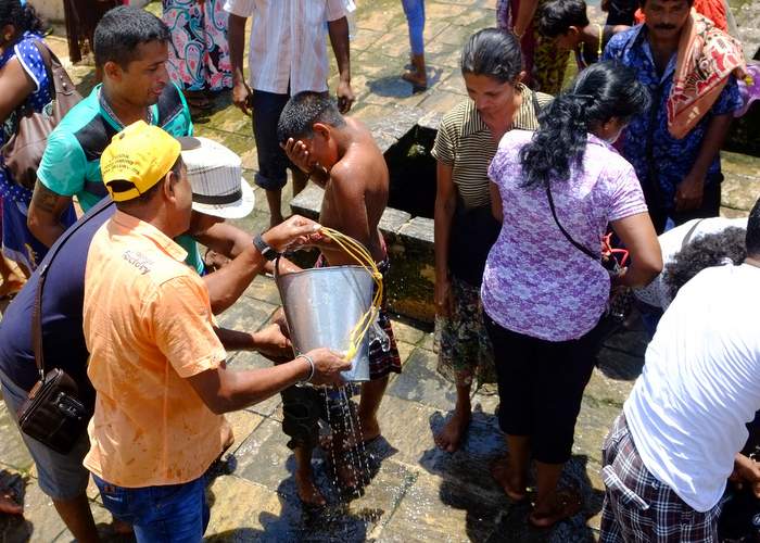 Families soak one another with bucketfuls of water hauled up from wells at the Kanniya hot springs, four miles northwest of Trincomalee. Photo for The Washington Post by Henry Wismayer.