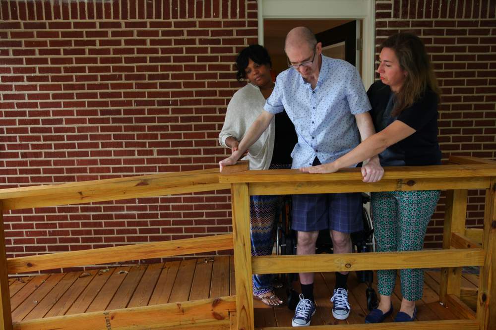 CNA Chloe Jones (left) and Beth Anne Harrill (right) assist Greg Germani on a new wheelchair ramp at his Decatur home. (Sean McNeil)