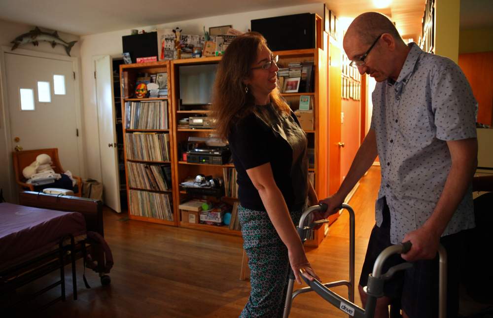 Beth Anne Harrill helps Greg Germani to his feet in their Decatur home. (Sean McNeil)