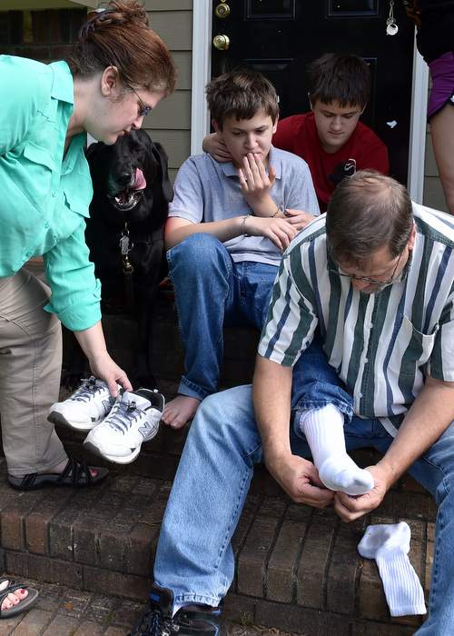 Jennifer and Michael  Schwenker prepare to take twin sons Sam (at back) and Ben, who have autism, for a walk in their Cobb County neighborhood.