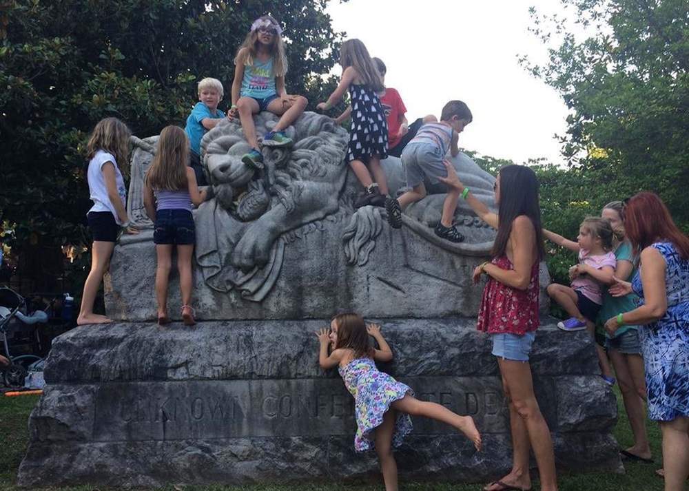 Henry (top left) and friends clamber on the Lion of the Confederacy statue at Oakland Cemetery during Tunes from the Tombs in June. The statue commemorates unknown soldiers of the Confederacy. Contributed photo