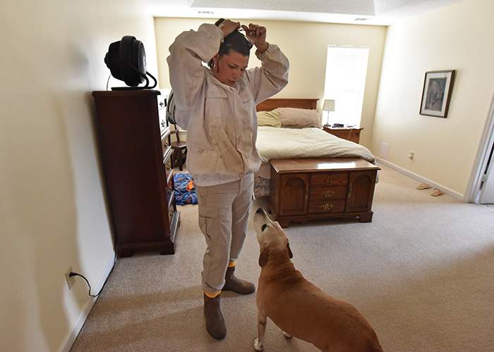 Anna suits up in preparation for checking the beehives in the backyard of her home in Perry. 